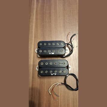Dvě černé humbuckery s viditelnými snímačmi a připojeným kabelážím. Horní snímač má bílý nápis V8 a spodní snímač má bílý nápis V7. Oba jsou umístěny…