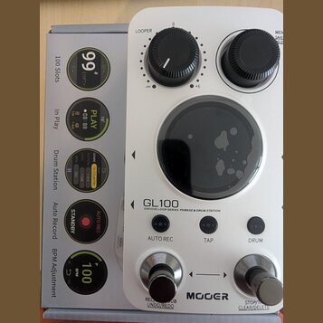Bílý přístroj s nápisem GL100 a podtitulem GROOVE LOOP SERIES PHRASE & DRUM STATION. Na spodní straně je logo MOGER a ovládací prvky s nápisy AUTO RE…