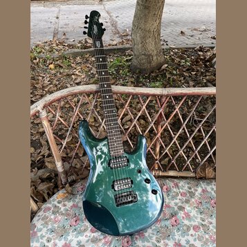 Kytara s tmavě zeleným kovovými lakem a hnědým hmatníkem. Na hlavě je bílý nápis "Schecter". Nástroj má dva humbuckery a fixační most. Povrch laku je…