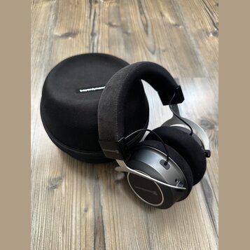 Černé sluchátka s kovovými prvky a velkými polstrováním v uších i na hlavě. Na sluchátkách je vidět nápis beyerdynamic v několika místech. Vedle sluc…
