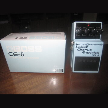 Kytarový efekt Boss CE-5 Chorus Ensemble v modré barvě s bílým ovládacím panelem. Na pedálu jsou nápisy CHECK, E.LEVEL, RATE, DEPTH, FILTER a OUTPUT…