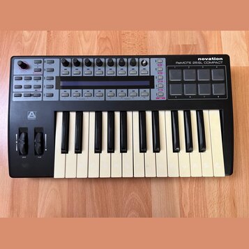 Černý MIDI kontrolér s klaviaturaí, značka novation a model ReMOTE 25SL COMPACT. Zařízení obsahuje klávesy, osm padů, osm otočných enkoderů a několik…