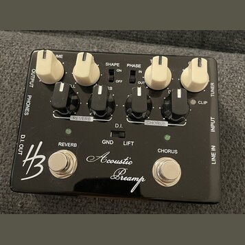 Černý kytarový efekt s nápisem Acoustic Preamp a logem HB. Zařízení má čtyři bílé otočné knoflíky, čtyři černé přepínače a dvě stříbrné tlačítka ozna…