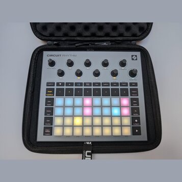 Šedý sampler Novation Circuit Rhythm v černém přepravním pouzdře. Horní část obsahuje osmi otočných ovladačů s popisky jako Master Volume, Start, Sto…