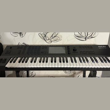 Černý klaviatura MPC s bílými a černými klávesami, umístěná na černém stojanu. Na pravé straně je bílý nápis AKAI PROFESSIONAL a pod ním MPC KEY 61.…