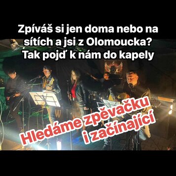 Fotografie zachicuje kapelu čtyř mužů a jedné ženy během hraní na pódiu. Jsou zde vidět elektrická kytara, akustická kytara a bicí souprava. V pozadí…