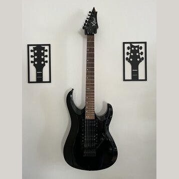 Černá elektrická kytara s hrotovitou hlavou a tmavým hnedým hmatníkem. Na hlavě je bílý nápis Xcart. Kytara má dva humbuckery, tremolo systém a je um…