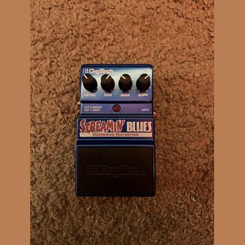 Modrý kytarový efekt s nápisy SCREAMIN' BLUES a OVERDRIVE/DISTORTION. Na pravé straně jsou čtyři ovládací knoflíky s popisky LEVEL, LOW, HIGH a GAIN…