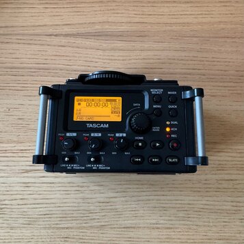 Černý digitální záznamový přístroj značky TASCAM s LCD displejem, na kterém je vidět nápis NO CARD. Zařízení má ovládací tlačítka DATA, MENU, QUICK a…