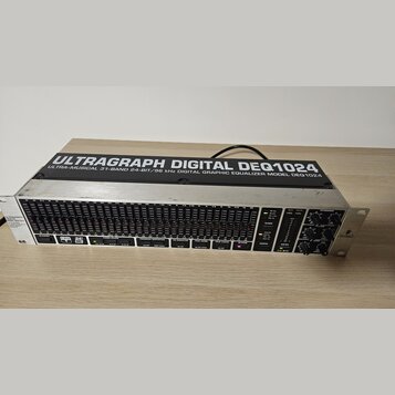 Digitální grafický ekvalizér v rackovém provedení s kovovým šasi. Na horní části je nápis ULTRAGRAPH DIGITAL DEQ1024 a pod ním text ULTRA-MUSICAL 31-…