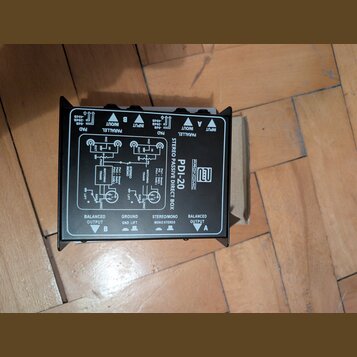 Černá pasivní DI box s nápisem STEREO PASSIVE DIRECT BOX a označením modelu PDI-20 pod logem PRONOMIC. Zařízení má na horní straně přepínače PAD a PA…