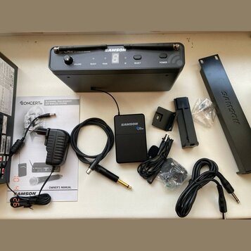 Sada bezdrátového systému značky SAMSON. Obsahuje černý přijímač s nápisem CR 88 UHF WIRELESS RECEIVER, malý černý vysílač s nápisem SAMSON CR 88 a p…