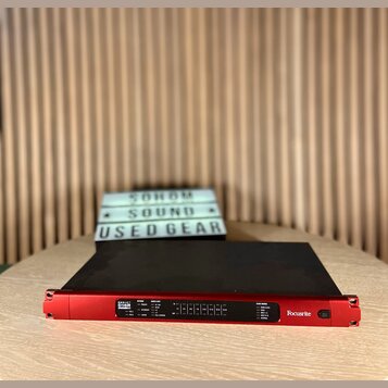 Červený rackový audio rozhraní s černým horním panelem. Na přední straně je bílý nápis REDUNIT D16R a logo Focusrite. Jsou zde viditelné ovládací prv…
