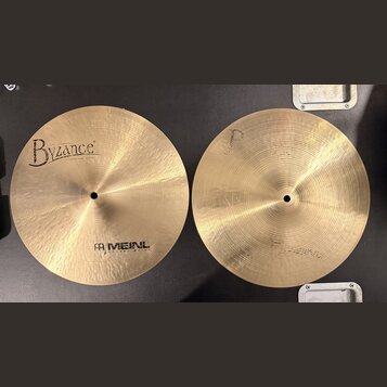 Dvě mosazné činely s jemným rýhováním povrchu. Levý činel nese nápisy „Byzance“ a „MEINL HOLANG MEINL“. Pravý činel nemá žádný viditelný nápis ani lo…