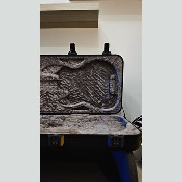 Otevřený tvrdý kufr na hudební nástroj s vnitřním polstrováním z šedého plyšového materiálu. Vnitřní prostor je tvarován pro kytaru nebo podobný nást…