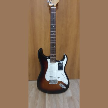 Elektrická kytara s tłem v barvě sunburst a bílým pickguardem. Na těle je nalepený štítek s nápisy PLAYER SERIES STRATOCASTER a logo Fender. Kytara m…