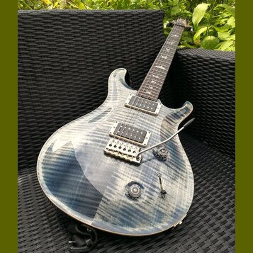 Elektrická kytara s modře žilkovaným povrchem těla a hnedým hřidlem. Na hmatníku je viditelné logo PRS. Kytara má dva humbuckery, pěticestný přepínač…