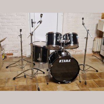 Černá bubnová sada značky TAMA. Sestava obsahuje basový buben, tommy a snare drum, vše v černém lakovaném provedení s chromovaným kováním. K sadě pat…