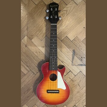 Akustická kytara s tělem v červeno-žlutém sunburst provedení a černou hlavou. Na hlavě je bílý nápis Epiphone a podpis Lee Perry. Nástroj má hnědý hm…