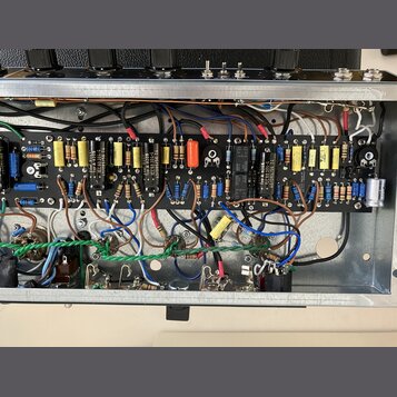 Fotografie zachycuje vnitřek elektronického zařízení s otevřeným šasi. Je viditelná černá základní deska osazená různými komponenty, jako jsou rezist…