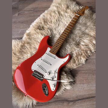 červená elektrická kytara s bílým pickguardem a hnědým hmatníkem. Na hlavě nástroje je viditelné logo Squier. Kytara má tři snímače, pětipositionní p…