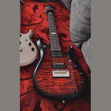 Elektrická kytara s červeným plamenovitým povrchem těla a černým hmatníkem. Na 12. pražci je viditelné logo "Ibanez". Kytara má dva humbuckery, chrom…