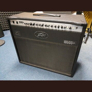 Kytarový kombo zesilovač s černým potahem a stříbrným ovládacím panelem. Na panelu je nápis 6505+ 112 a logo Peavey. Přední mřížka je černá s vyšívan…