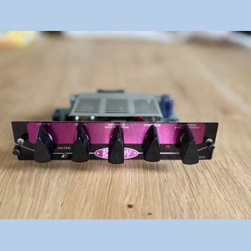 Černý kytarový zesilovač s fialovým předním panelem. Na panelu jsou čtyři černé otočné knofíky s nápisy DRIVE, BASS, MIDDLE PULL/CHANNEL a TREBLE, dá…