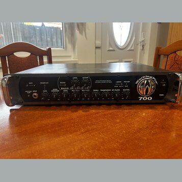 Černý basový zesilovač v rackovém provedení s kovovými úchyty po stranách. Na předním panelu je nápis PROFESSIONAL BASS AMPLIFIER a logo WorkingPro s…