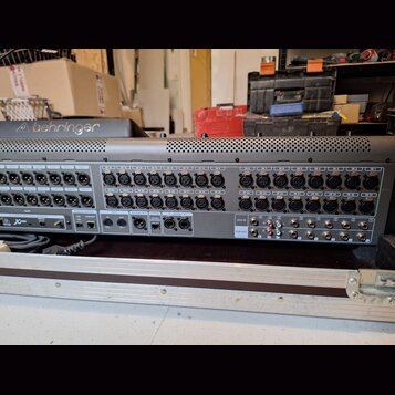 Šedý rackový stagebox s řadou vstupních konektorů. Na horní části je viditelné logo behringer a v pravé části jsou vstupy označené od IN 1 do IN 24.…