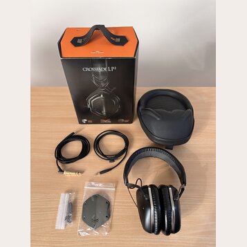 Na fotografii je sada sluchátek s příslušenstvím. Je zde černý papírový box s oranžovým vrchem a nápisy CROSSFADE LP2, milano design a vmoda. Součást…