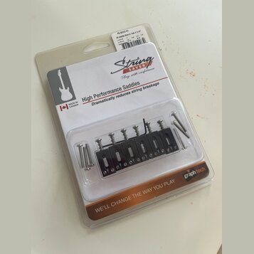 Plastové balení s náhradními kobylkovými sedly a šrouby. Na obalu je nápis String SAVER, High Performance Saddles, Dramatically reduces string breaka…