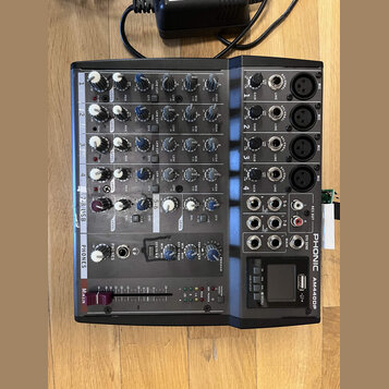 Šedý mixážní pult s černými ovládacími prvky a nápisy. Na pravé straně je vertikálně uveden název značky PHONIC a model AM440DP. Zařízení obsahuje čt…