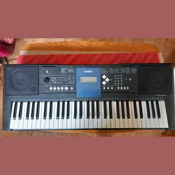 Černý digitální klavír značky YAMAHA s modelem EZ300. Nástroj má bílé a černé klávesy, dvě integrovaná reproduktory po stranách a ovládací panel s di…