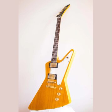 Elektrická kytara s žlutým lakem a bílým plechtrzem. Na hlavě hředu je nápis Epiphone. Kytara má dva humbuckery, zlatý hardware a tři ovládací knoflí…