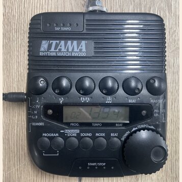 Černý rytmický doprovod TAMA RHYTHM WATCH RW200 s digitálním displejem a ovládacími tlačítky. Na horní části je nápis TAP TEMPO a vprostřed logo TAMA…