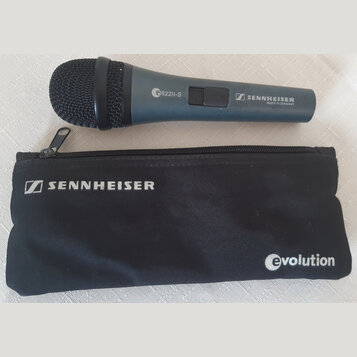 Modrý dynamický mikrofon s černou mřížkou a černým pouzdrem. Na těle mikrofonu je bílý nápis e822II-S a logo SENNHEISER s doplňkem MADE IN GERMANY. N…