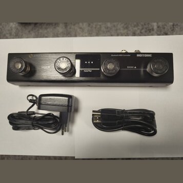 Černý Bluetooth MIDI Controller značky HOTONE s logem AMPERO. Zařízení má čtyři kovové spínací knoflíky, nápisy BANK s šipkami a displej s textem PC…