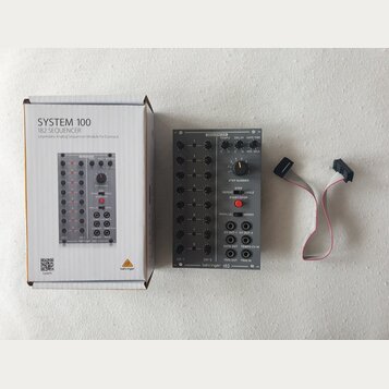Krabice a modul sekvenceru s připojeným datovým kabelem. Na krabici je nápis SYSTEM 100 182 SEQUENCER Legendary Analog Sequencer Module for Eurorack…
