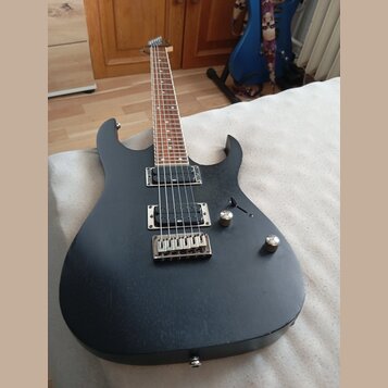 Černá elektrická kytara s matným povrchem a hnědým hmatníkem. Nástroj má dva humbuckery, jeden ovládací knoflík hlasitosti a jeden tón. Na těle jsou…