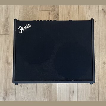 Černý kytarový kombo zesilovač s texturovaným povrchem. V levém horním rohu je bílé logo Fender. Horní hrana obsahuje ovládací prvky v podobě několik…
