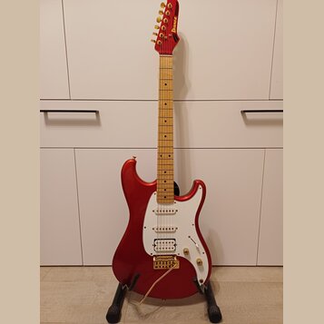 červená elektrická kytara s jasným lakem a hnědým hmatníkem. Na hlavě je zlatý nápis Ibanez a na těle se nachází bílý pickguard s třemi snímači. Kyta…