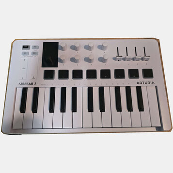 Bílá MIDI klaviatura s názvy MINILAB 3 a ARTURIA. Horní panel obsahuje osm bílých otočných knoflíků, čtyři posuvníky a řadu ovládacích tlačítek s náp…