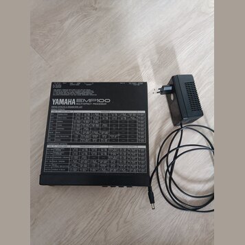 Černý efektový procesor YAMAHA EMP100 MULTI-EFFECT PROCESSOR s bílým tabulkovým přehledem parametrů na horní straně. Zařízení má v zadní části konekt…