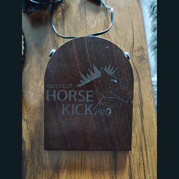 Tmavě hnědý dřevěný pedál s oblým horním okrajem. Na povrchu je vyryto logo koně a nápisy ORTEGA®, HORSE KICK PRO. Povrch vykazuje drobné škrábance a…