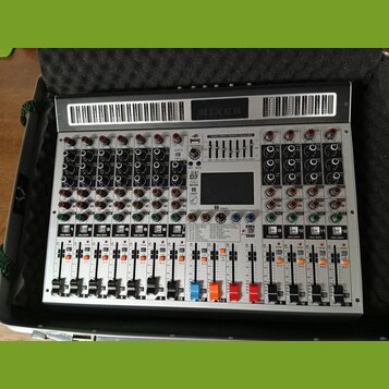 Stříbrný mixážní pult v přepravním kufru s pěnovou výplní. Na horní části je nápis MIXER a v centru se nachází displej s nadpisem 7-BAND STEREO GRAPH…