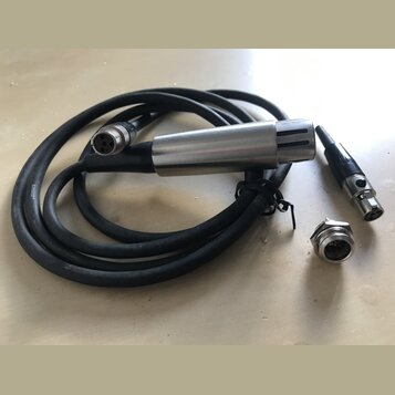 Na fotografii je černý kabel s kovovým cylindrickým koncem, který má v horní části svislé rýhy. Na kabelu je viditelný bílý nápis SHURE. Součástí jso…