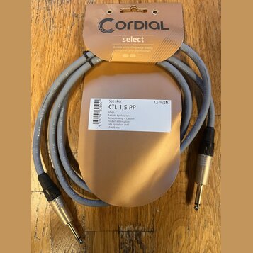 Šedý audio kabel s konektory typu jack na obou koncích, umístěný v původním hnědém papírovém balení. Na balení je nápis Cordial select a štítky s tex…