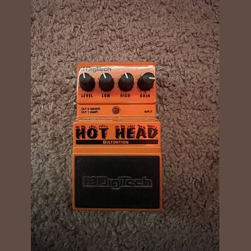 Oranžový kytarový efekt s nápisem HOT HEAD DISTORTION a logem DigiTech v horní části i na spodním černém panelu. Na horní straně jsou čtyři černé oto…