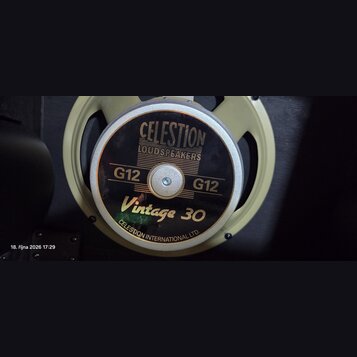 Fotografie zachycuje reproduktor s béžovým kovovým rámem. Na středovém krytu je černý štítek s nápisy CELESTION LOUDSPEAKERS, G12, Vintage 30 a v dol…